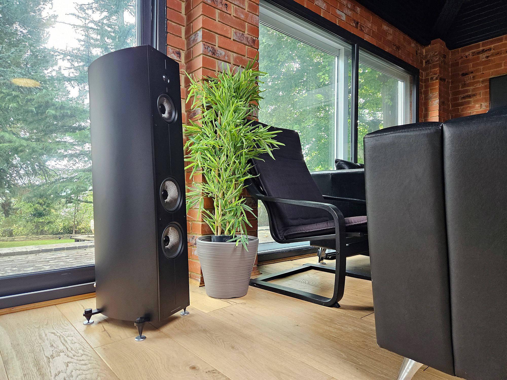 Acoustic Energy Corinium negro mate en un loft con plantas